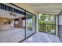 View of the living room through sliding glass doors leading to a tiled balcony with a view of the pool at 700 Starkey Rd # 1145, Largo, FL 33771