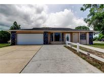 Charming single-story home featuring a spacious driveway and a well-maintained lawn with a white fence at 8200 Westfield Dr, Port Richey, FL 34668