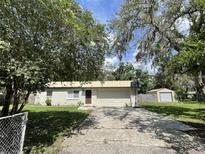 Charming single-story home with a metal roof, mature trees, spacious driveway and a detached garage at 9844 Xenia St, New Port Richey, FL 34654