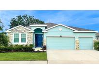 Charming single-Gathering home with a well-manicured lawn, stone accents, and a vibrant blue door at 10702 Laxer Cay Loop, San Antonio, FL 33576