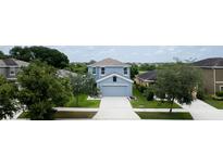 Two-story light-blue home with a gray roof, a two-car garage and a well-manicured lawn at 11926 Grand Kempston Dr, Gibsonton, FL 33534