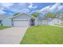 Charming single-story home featuring a well-manicured lawn, tidy landscaping, and attached two-car garage at 13916 Briardale Ln, Tampa, FL 33618
