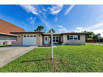 Charming single-story home with a well-manicured lawn, a white garage door and a welcoming front entrance at 1800 Mapleleaf Blvd, Oldsmar, FL 34677