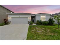 Charming single-story home features a two-car garage, stone accents, and landscaped front yard at dusk at 2518 Chapel Oak Bnd, Wesley Chapel, FL 33543