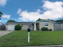 Charming single-story home featuring a well-manicured lawn, attached garage and inviting covered entry at 3811 Elmwood Dr, Holiday, FL 34691