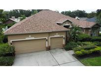 Tan home with a two-car garage, concrete driveway, and well-manicured landscaping surrounding the property at 8731 Tantallon Cir, Tampa, FL 33647