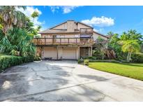 Two-story home with a large deck, two-car garage, and a spacious driveway surrounded by lush greenery at 101 Carlyle Dr, Palm Harbor, FL 34683
