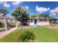 Charming single-story home featuring a front yard with a tree and a bright blue front door at 12113 Victory Dr, Hudson, FL 34667