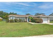 Charming single-story home featuring a well-maintained lawn and beautiful, mature landscaping at 13311 Omega Ct, Dade City, FL 33525