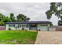 Charming single-story home with a well-manicured lawn, brick driveway, and light blue exterior at 2192 Robinson Dr, St Petersburg, FL 33710