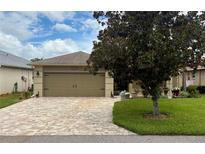 Charming home featuring a two-car garage with a brick-paved driveway and lush lawn at 29524 Waggle Dr, San Antonio, FL 33576