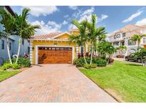 Charming home with a well-manicured lawn, brick driveway, and a beautiful wood garage door surrounded by palm trees at 539 Treviso Dr, Apollo Beach, FL 33572