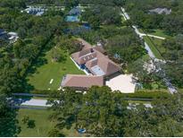 Expansive estate featuring a beautiful brown roof, surrounded by lush greenery and a private tennis court at 1835 Alicia Way, Clearwater, FL 33764