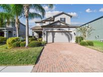 Charming two-story home featuring a brick driveway, two-car garage, and well-manicured landscaping at 19656 Long Lake Ranch Blvd, Lutz, FL 33558