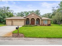 Beautiful home featuring a well-manicured lawn, three-car garage, and arched entryway, providing curb appeal at 2409 Heather Manor Ln, Lutz, FL 33549