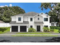 Charming two-story home featuring a modern design with stone accents, black trim, and an attached two-car garage at 4111 W Mullen Ave, Tampa, FL 33609