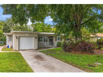 Charming home featuring a well-manicured lawn, a driveway, an attached garage, and lovely landscaping at 4321 S Thatcher Ave, Tampa, FL 33611