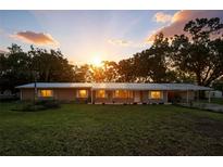 Charming single-story home with lush lawn and a metal roof bathed in the warm glow of the setting sun at 4708 Bugg Rd, Plant City, FL 33567