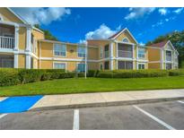 Inviting condo complex featuring well-maintained landscaping, yellow facades, and white accents under a bright blue sky at 9481 Highland Oak Dr # 1506, Tampa, FL 33647
