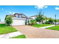 Charming two-story home featuring a brick driveway, attached garage, and well-manicured landscaping at 10842 Rolling Moss Rd, Tampa, FL 33647