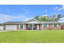 Charming brick home featuring a well-manicured lawn, attached garage, and a cozy front porch at 2106 Sherbrook Dr, Valrico, FL 33594