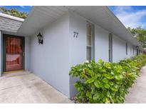 Light gray condo exterior with a black entry door and green shrubbery at 4160 Fruitville Rd # 77, Sarasota, FL 34232