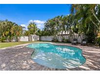 Inviting backyard pool surrounded by lush tropical landscaping, white fencing, and brick pavers at 5107 W Platt St, Tampa, FL 33609