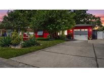Charming red home featuring a well-manicured lawn and spacious driveway leading to an attached two-car garage at 5501 Highland S St, St Petersburg, FL 33705