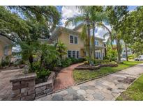 Charming yellow two-story home with lush landscaping, brick path, and a patterned driveway at 635 Bay Ne St, St Petersburg, FL 33701