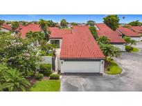 Charming home featuring a vibrant red tile roof, white garage door, and beautiful, lush landscaping at 780 Sarabay Rd # 16, Osprey, FL 34229
