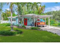 Charming home with a bright red door, lush green lawn, a covered carport, and tropical landscaping at 1042 S Sterling Ave, Tampa, FL 33629