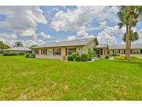 Charming home exterior features a large, well-maintained lawn and mature palm trees, with red shutters on the windows at 1905 Canterbury Ln # 17, Sun City Center, FL 33573