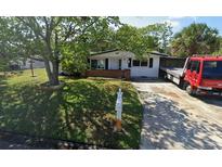 Cozy single-story home featuring a well-maintained lawn and mature trees in a sunny neighborhood at 6338 Nashua Dr, Port Richey, FL 34668