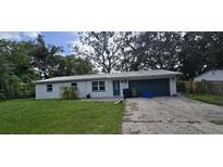 Single-story home features a metal roof, blue front door, attached garage and concrete driveway at 10918 N Boulevard, Tampa, FL 33612