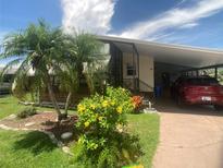 Charming single-story home with a covered parking area, lush landscaping, and vibrant flowers at 1710 7Th Sw St # 39, Ruskin, FL 33570