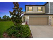 Two-story home boasting a two-car garage, stone accents, and lush landscaping under a twilight sky at 17741 Tawny Malt Pl, Land O Lakes, FL 34638