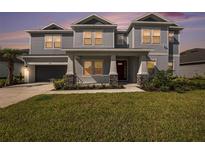 Beautiful two-story home featuring manicured lawn, covered porch with stone accents, and neutral color palette at 2492 Overfalls Pl, Wesley Chapel, FL 33543