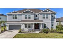 Charming two-story home featuring a manicured lawn, attached garage, and covered entryway at 2492 Overfalls Pl, Wesley Chapel, FL 33543