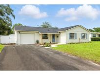 Charming single-story home featuring a brick exterior, blue shutters, manicured lawn and long driveway at 4611 W Bay Court Avenue, Tampa, FL 33611