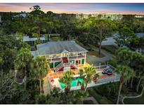 Stunning aerial view of a two-story home with a swimming pool, surrounded by lush greenery and palm trees at 4915 South Rd, New Port Richey, FL 34652