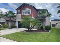 Charming two-story home with a well-manicured lawn and palm trees adding to its curb appeal at 1596 Ludington Ave, Wesley Chapel, FL 33543