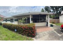 Charming single-story home featuring a covered porch, vibrant landscaping, and a brick-paved driveway at 4611 W Mcelroy Ave, Tampa, FL 33611