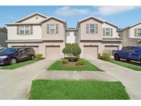 Well-maintained townhomes with a landscaped yard and individual driveways at 4935 White Sanderling Ct, Tampa, FL 33619