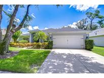 Charming single-story home featuring a well-manicured lawn, colorful landscaping, and a two-car garage at 15126 Shearcrest Dr, Lithia, FL 33547