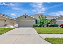 Charming one-story home with a well-manicured lawn, lush landscaping, and a wide driveway at 18164 Turning Leaf Cir, Land O Lakes, FL 34638