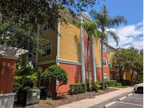 Exterior view of a multi-story condo building with bright colors, landscaping, and palm trees on a sunny day at 4207 S Dale Mabry Hwy # 6212, Tampa, FL 33611