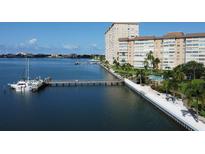 Waterfront condo complex featuring manicured landscaping, a swimming pool, and a private dock at 5108 Brittany S Dr # 405, St Petersburg, FL 33715