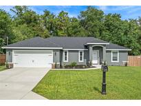 Beautiful single-story home with gray siding, well-manicured lawn, and a two-car garage at 6103 Fairway Dr, Ridge Manor, FL 33523