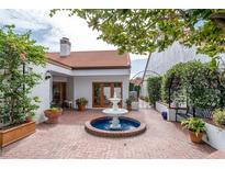 Charming courtyard with brick paving, a central fountain, lush greenery, and seating, perfect for relaxation and entertaining at 11503 Robles Del Rio Pl, Temple Terrace, FL 33617