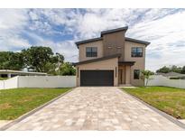 Contemporary two-story home featuring a paver driveway, black garage door, and manicured lawn at 1808 W Erna Dr, Tampa, FL 33603